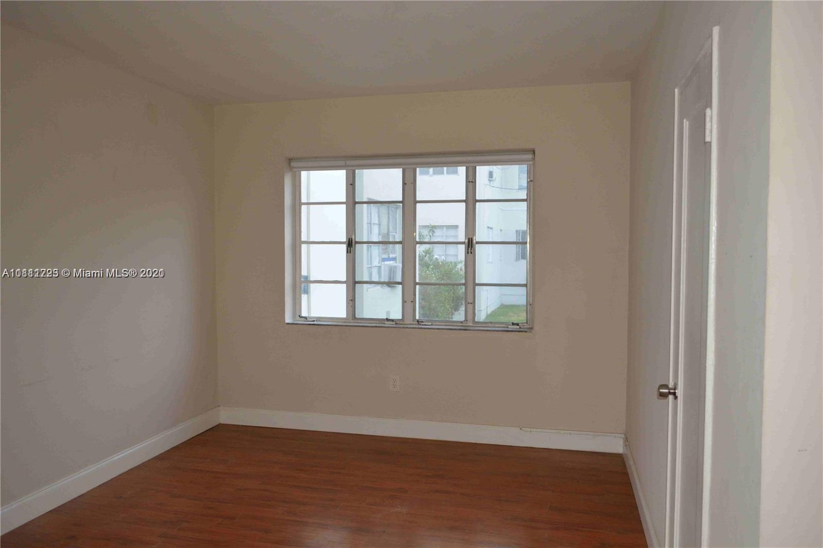 635 83rd Street, Unit 47 Miami Beach, FL 33141 - Photo 15 of 16 an empty room with wooden floor and windows
