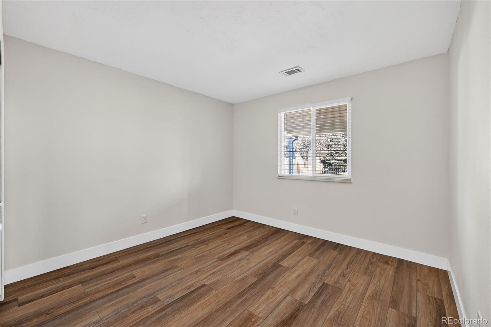 7586 Chase Street Arvada, CO 80003 - Photo 17 of 35 a view of an empty room with wooden floor and a window