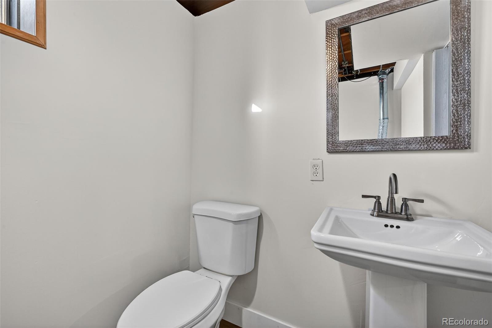 7586 Chase Street Arvada, CO 80003 - Photo 32 of 35 a bathroom with a toilet a sink and mirror