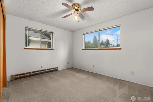 a view of an empty room with window and a ceiling fan