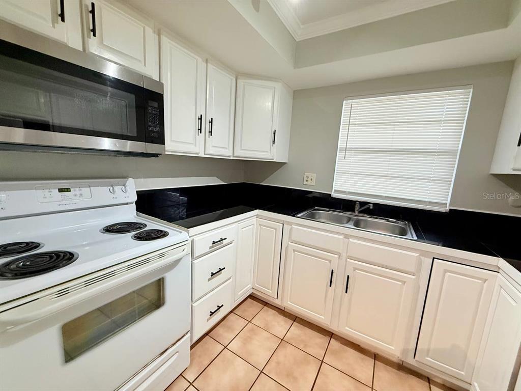 727 Milwaukee Avenue, Unit 6 Dunedin, FL 34698 - Photo 6 of 18 a kitchen with white cabinets and white appliances