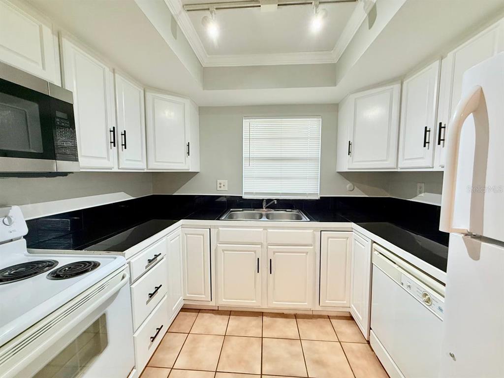 727 Milwaukee Avenue, Unit 6 Dunedin, FL 34698 - Photo 7 of 18 a kitchen with granite countertop white cabinets and white appliances