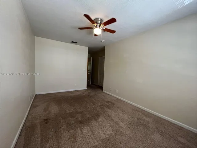 an empty room with closet and ceiling fan