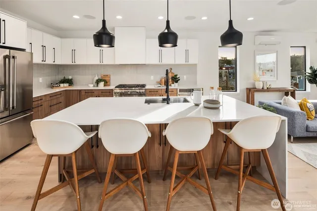 a large kitchen with kitchen island granite countertop a dining table chairs and white cabinets