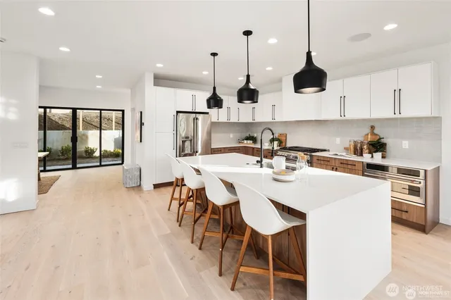 a kitchen with stainless steel appliances kitchen island granite countertop a sink a stove and a refrigerator