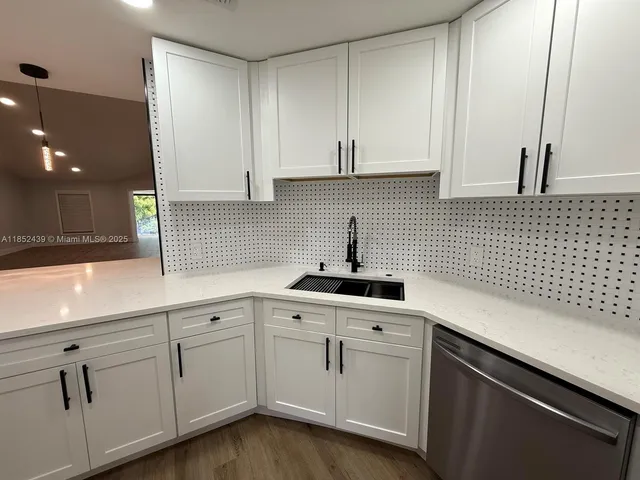a kitchen with white cabinets and sink