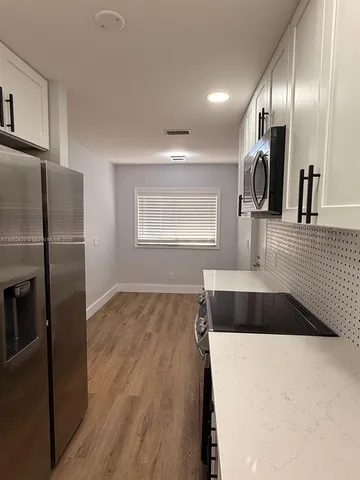 a large white kitchen with a refrigerator and a sink
