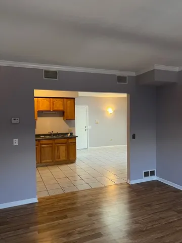 a view of kitchen and empty room with wooden floor