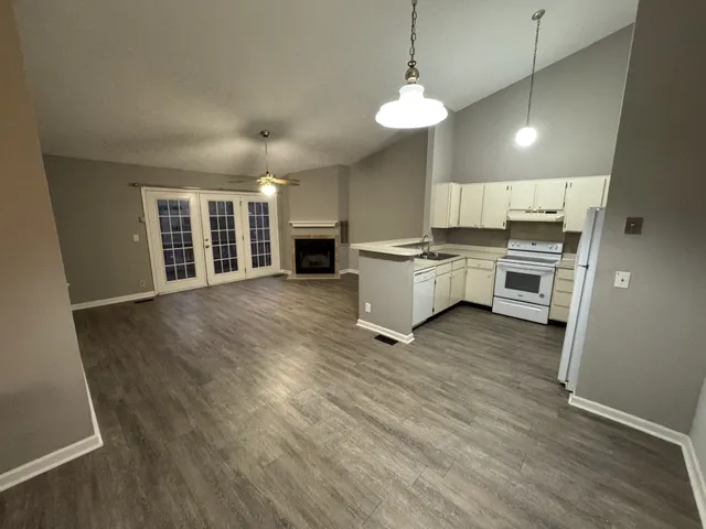 a kitchen with kitchen island granite countertop a stove top oven a sink a dining table and chairs with wooden floor