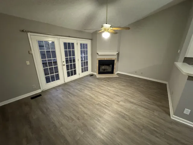 an empty room with wooden floor fireplace and chandelier