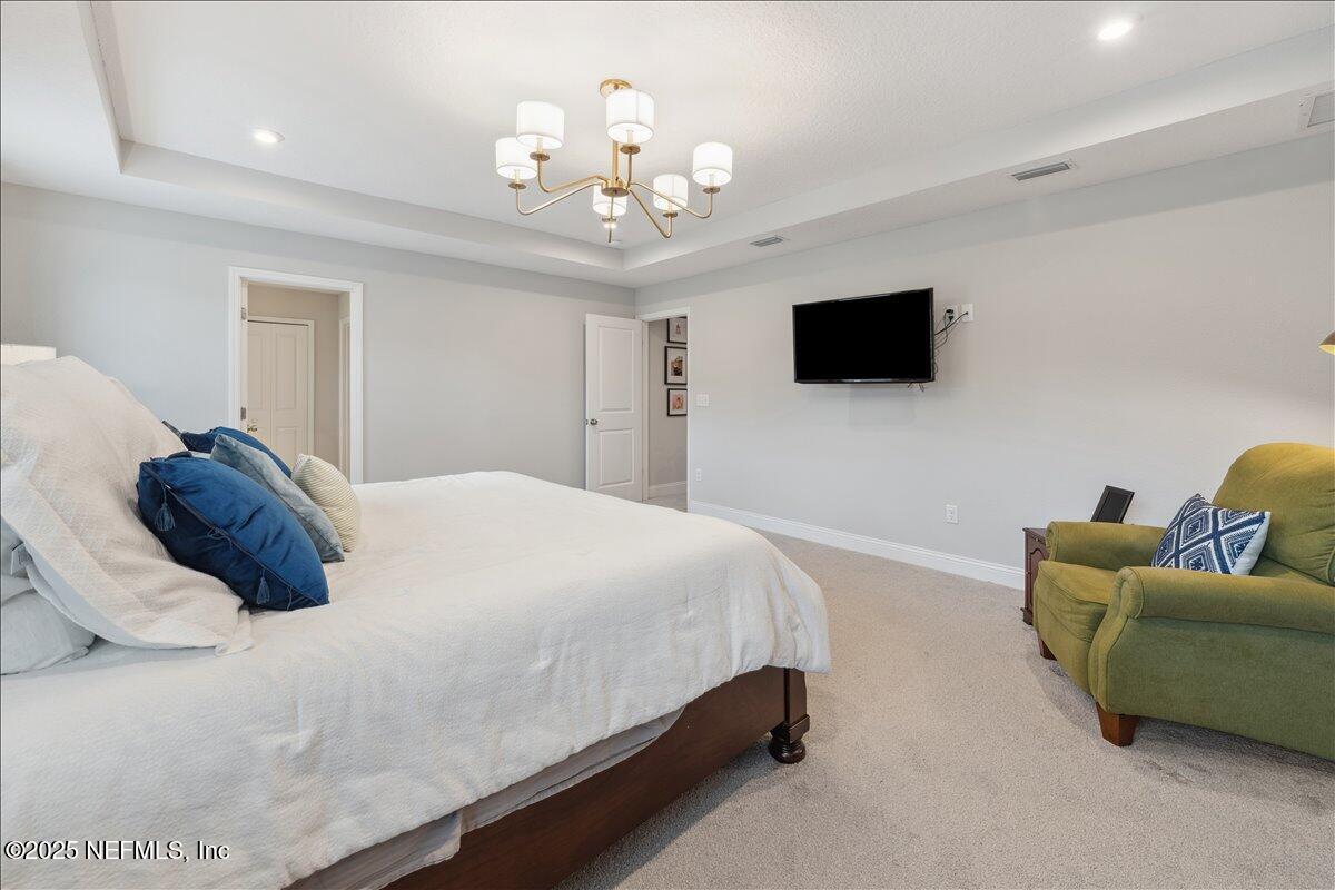 552 Meadow Creek Drive St. Johns, FL 32259 - Photo 23 of 62 a bedroom with a bed a couch and a flat screen tv