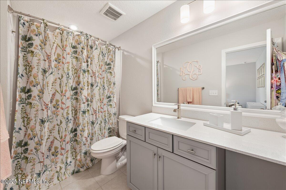 552 Meadow Creek Drive St. Johns, FL 32259 - Photo 25 of 62 a bathroom with a sink toilet a mirror and shower curtain