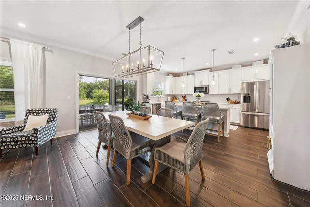 a dining room with stainless steel appliances kitchen island granite countertop furniture wooden floor and a chandelier