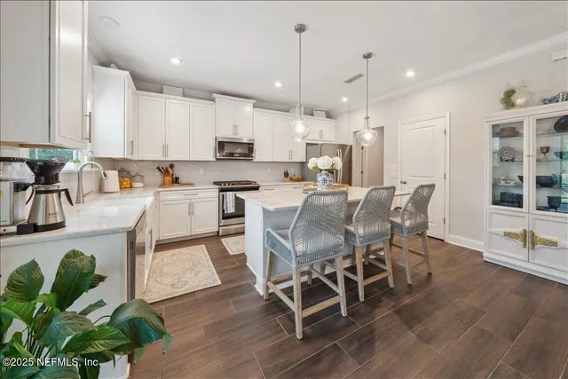 a kitchen with stainless steel appliances granite countertop a stove top oven a sink a dining table and chairs with wooden floor