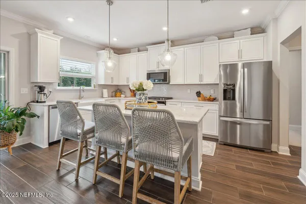 a kitchen with stainless steel appliances a dining table chairs refrigerator and sink