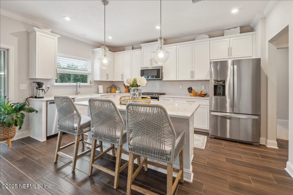 552 Meadow Creek Drive St. Johns, FL 32259 - Photo 9 of 62 a kitchen with stainless steel appliances a dining table chairs refrigerator and sink