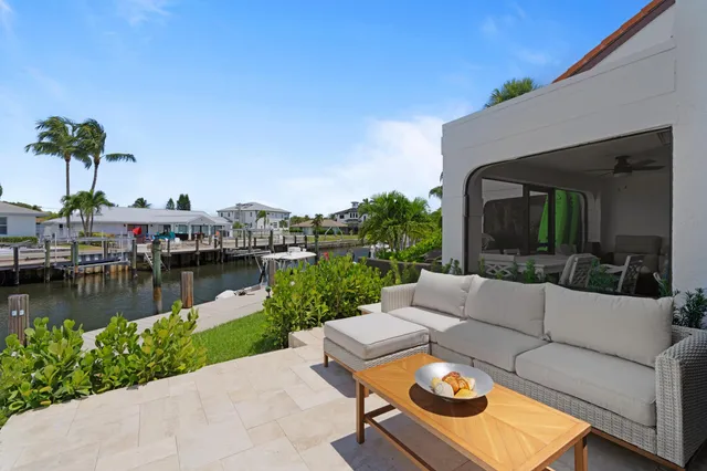 a view of a lake with couches table and chairs under an umbrella with large trees