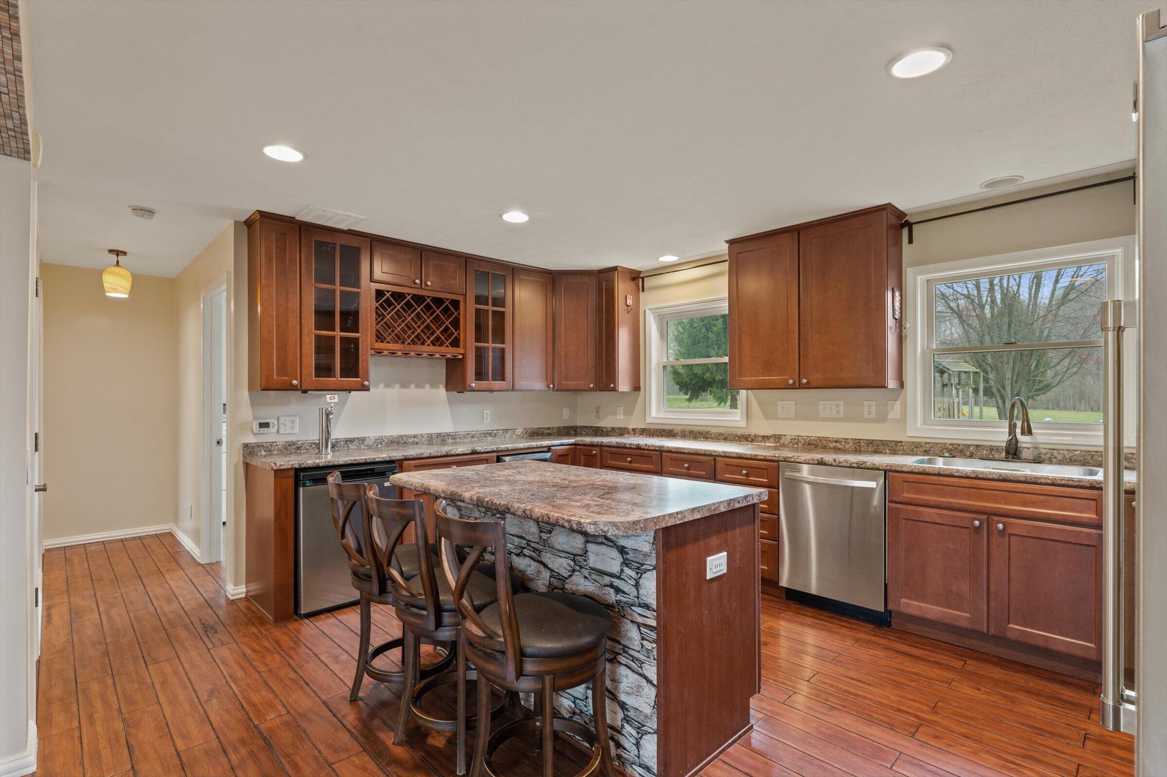 7692 North Emery Road Rolling Prairie, IN 46371 - Photo 14 of 69 a kitchen with stainless steel appliances granite countertop wooden floors and wooden cabinets