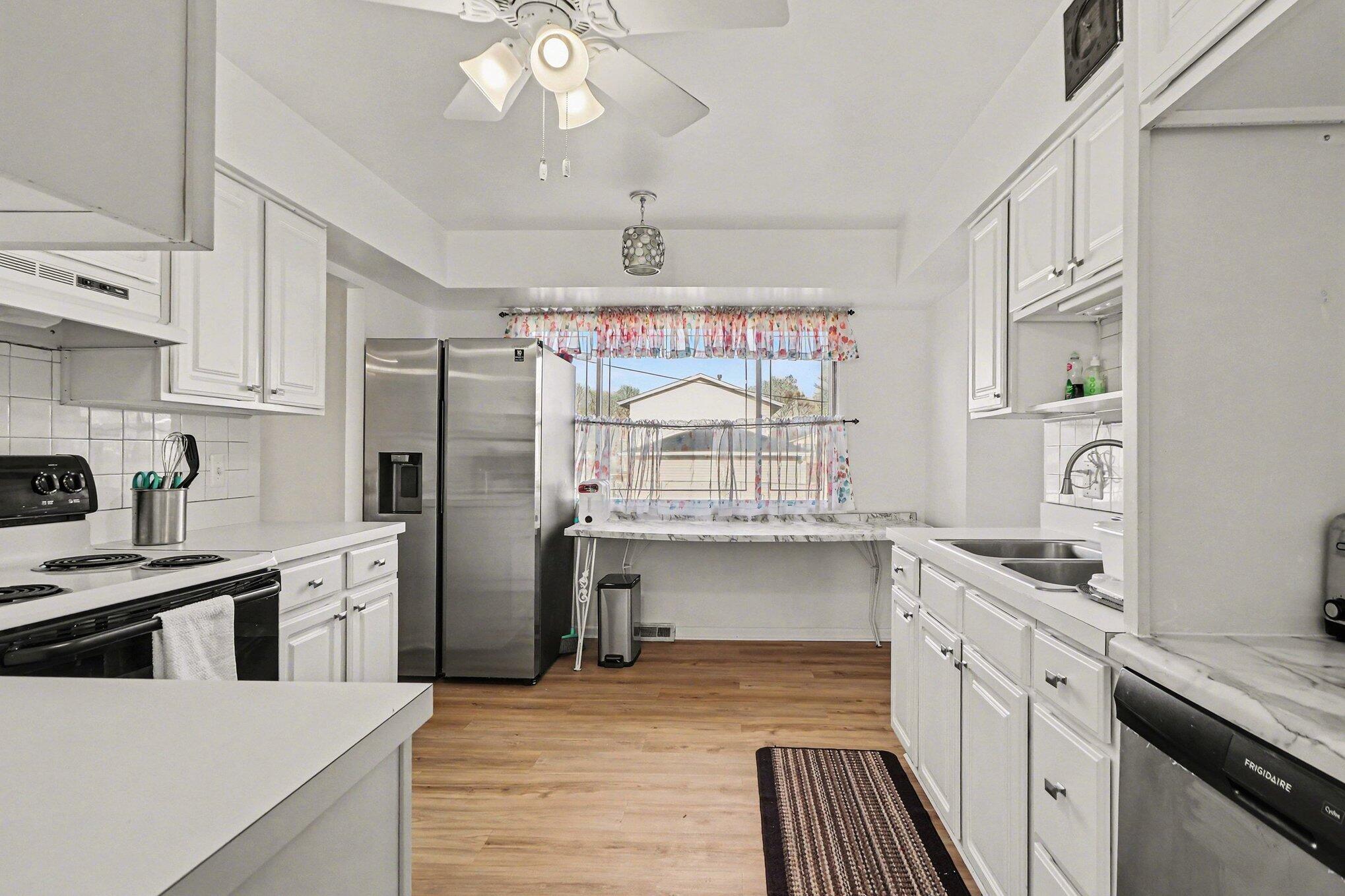 551 Union Place Gary, IN 46403 - Photo 14 of 28 a kitchen with stainless steel appliances a stove a sink dishwasher a refrigerator white cabinets and wooden floor
