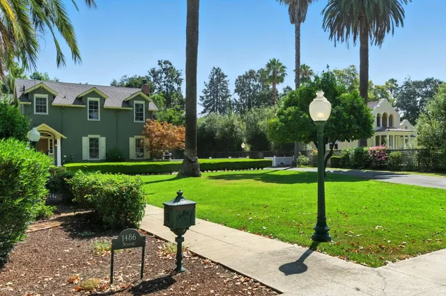 a front view of a house with garden and a tree