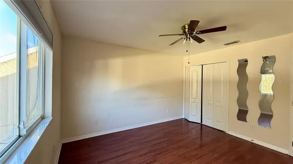 a view of a walk in closet with wooden floor and windows