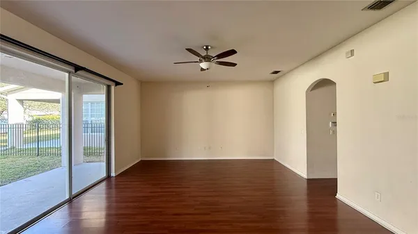 an empty room with wooden floor and a ceiling fan