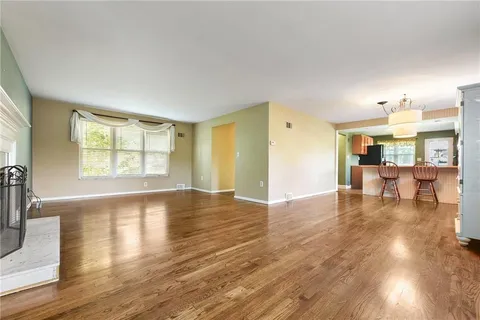 a view of an empty room with window and wooden floor