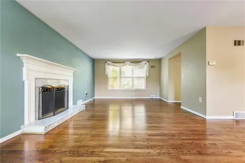 a view of an empty room with window and wooden floor