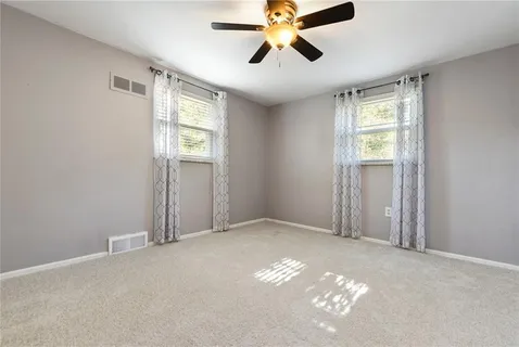 a view of an empty room with window and chandelier fan