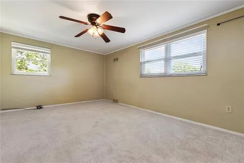an empty room with ceiling fan and windows
