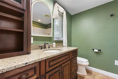 a bathroom with a granite countertop toilet sink and mirror