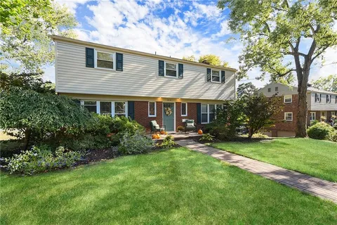 a front view of a house with a yard and trees