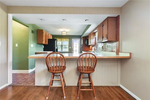 a kitchen with stainless steel appliances a table chairs and wooden floor