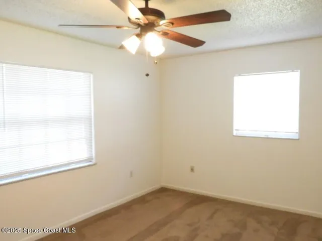 an empty room with a window and a fan