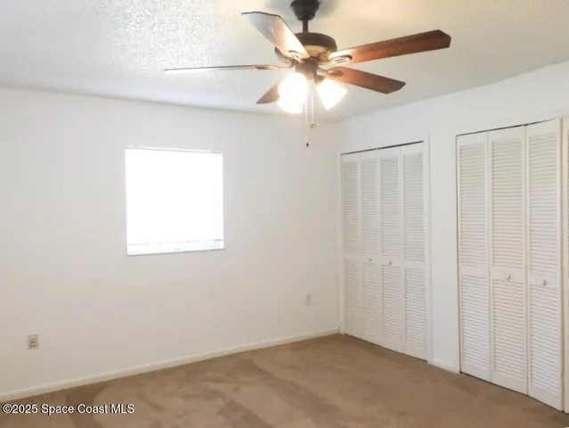 an empty room with a window and a fan