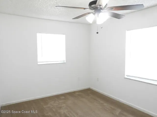 an empty room with a window and a fan