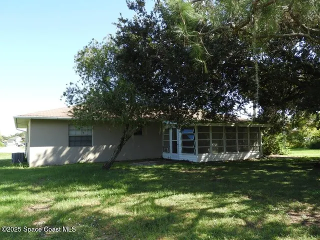 a view of a house with a yard and a large tree