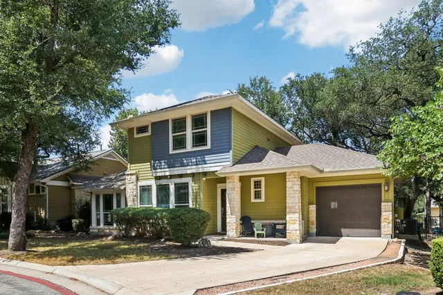 a front view of a house with yard and trees in the background