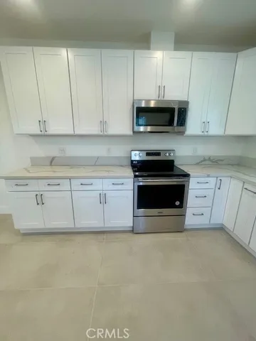 a kitchen with stainless steel appliances granite countertop a stove a sink and a white cabinets