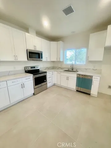 a kitchen with stainless steel appliances granite countertop a stove top oven a sink a refrigerator and white cabinets