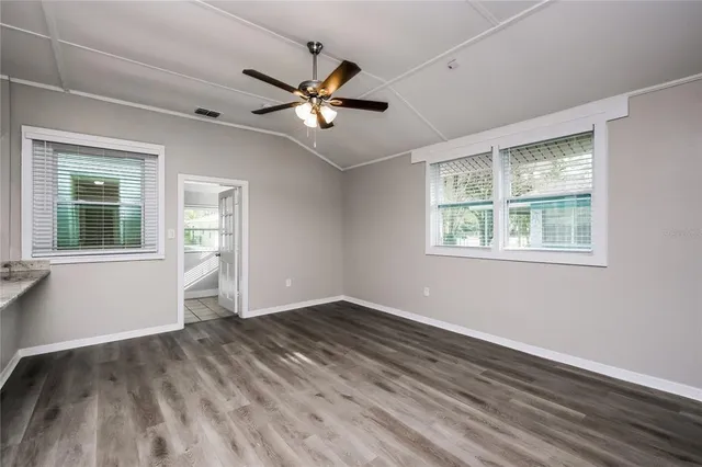 a view of empty room with wooden floor and fan