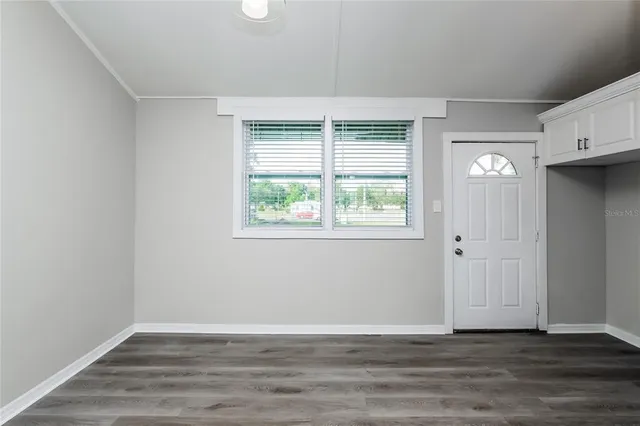 a view of an empty room with wooden floor and a window
