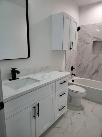 a bathroom with a granite countertop toilet sink and mirror
