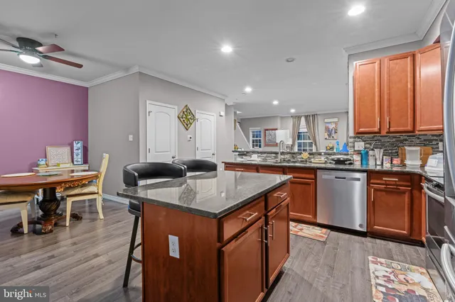 a kitchen with stainless steel appliances granite countertop a table chairs sink and wooden floor