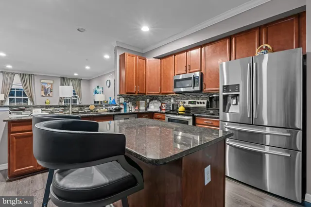 a kitchen with stainless steel appliances granite countertop a refrigerator a stove a sink a microwave and a refrigerator