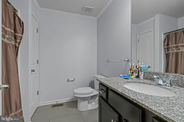 a bathroom with a granite countertop sink a toilet and a mirror