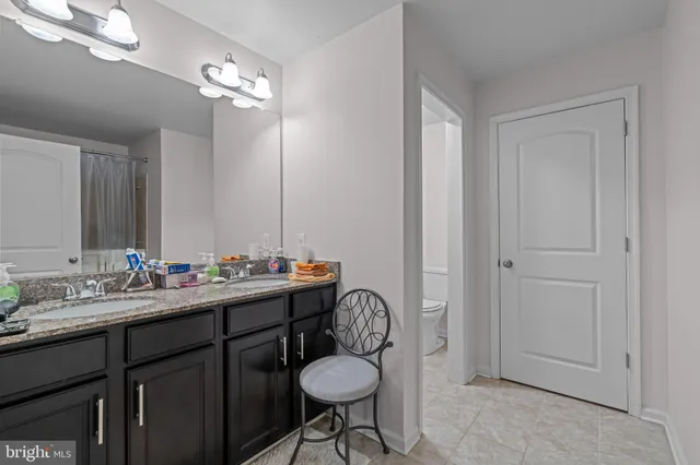 a bathroom with a granite countertop sink a toilet and mirror