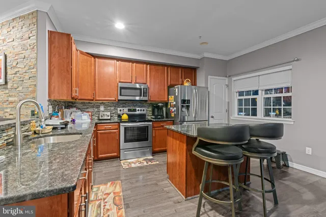 a kitchen with stainless steel appliances granite countertop a stove top oven a sink dishwasher a dining table and chairs with wooden floor