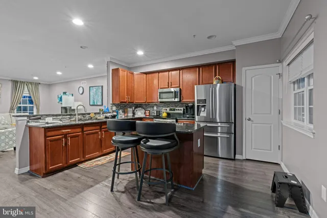 a kitchen with stainless steel appliances granite countertop a refrigerator a stove top oven a sink dishwasher and wooden cabinets with wooden floor