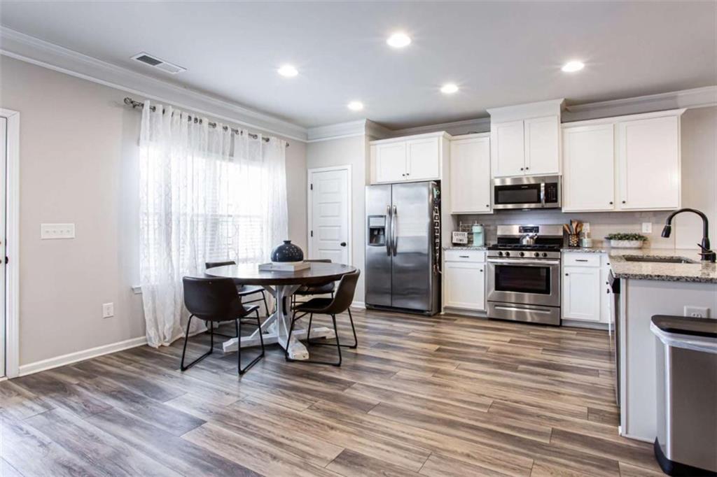 95 Bromes Street Lawrenceville, GA 30046 - Photo 5 of 37 a kitchen with a sink a stove a refrigerator and white cabinets with wooden floor